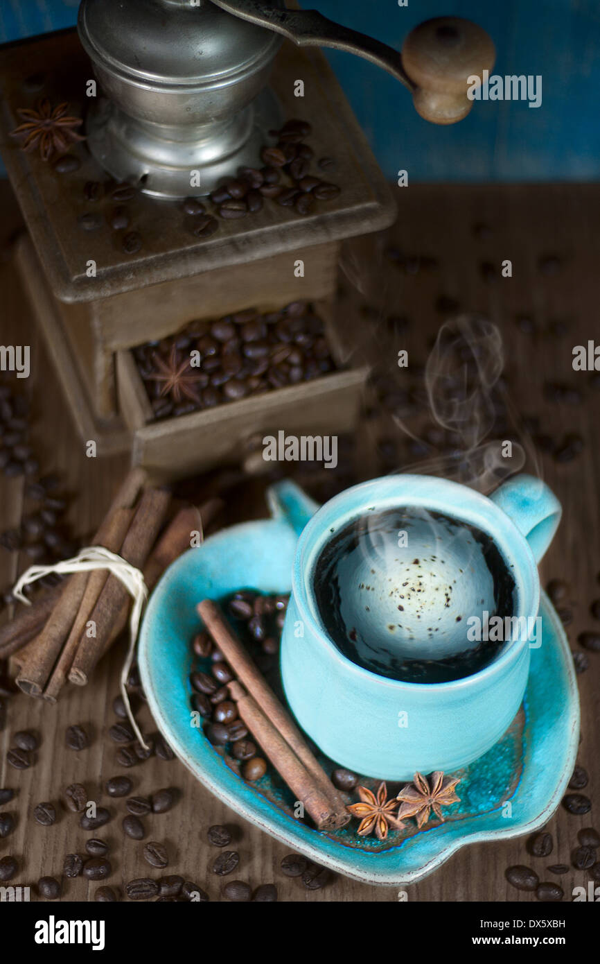 Coffee in the teal mug and old teal mill with cinnamon and star anise. Selective focus. Stock Photo