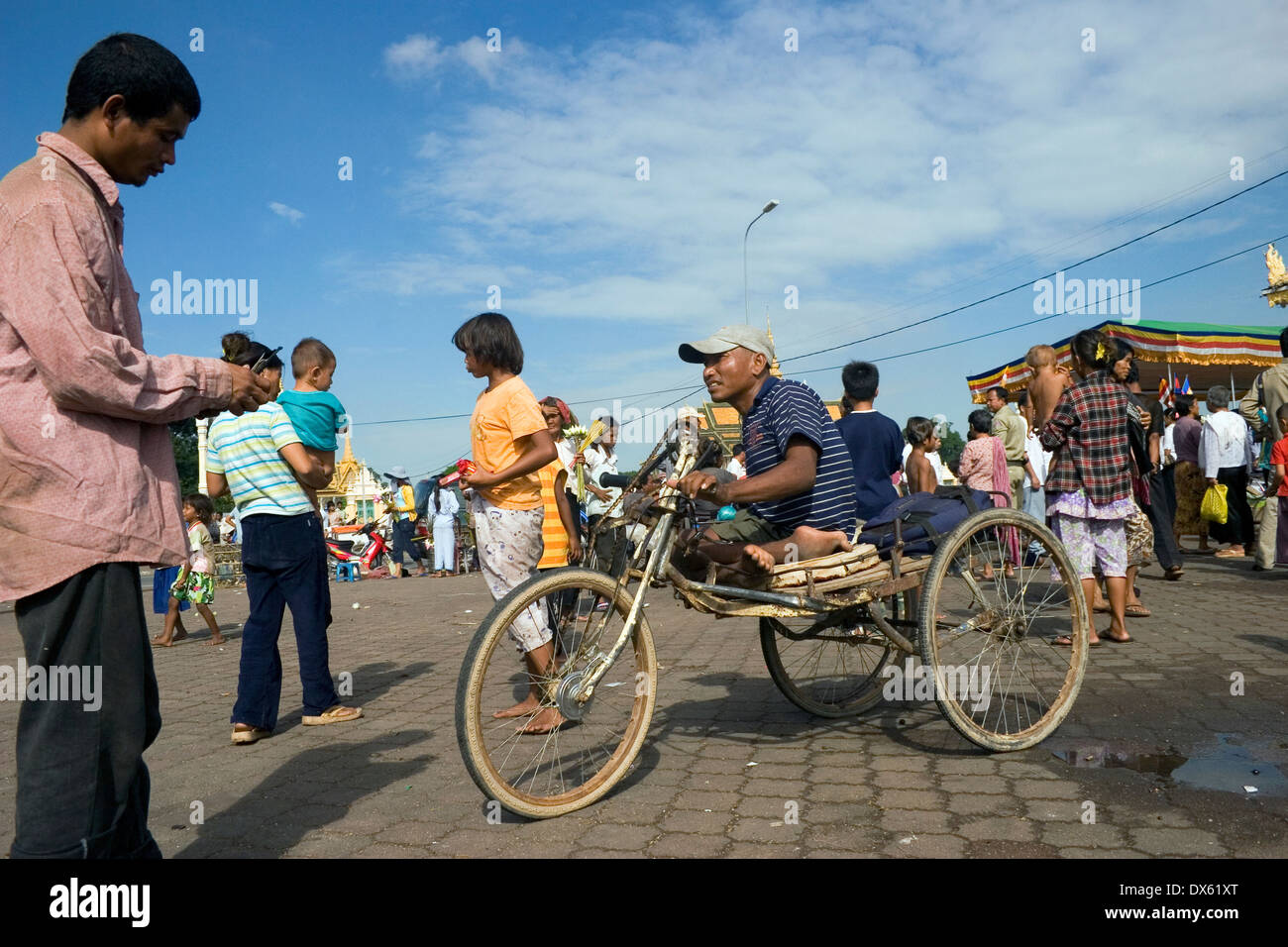 A handicapped man confined to a wheelchair is peddling with his hands on the Mekong riverside