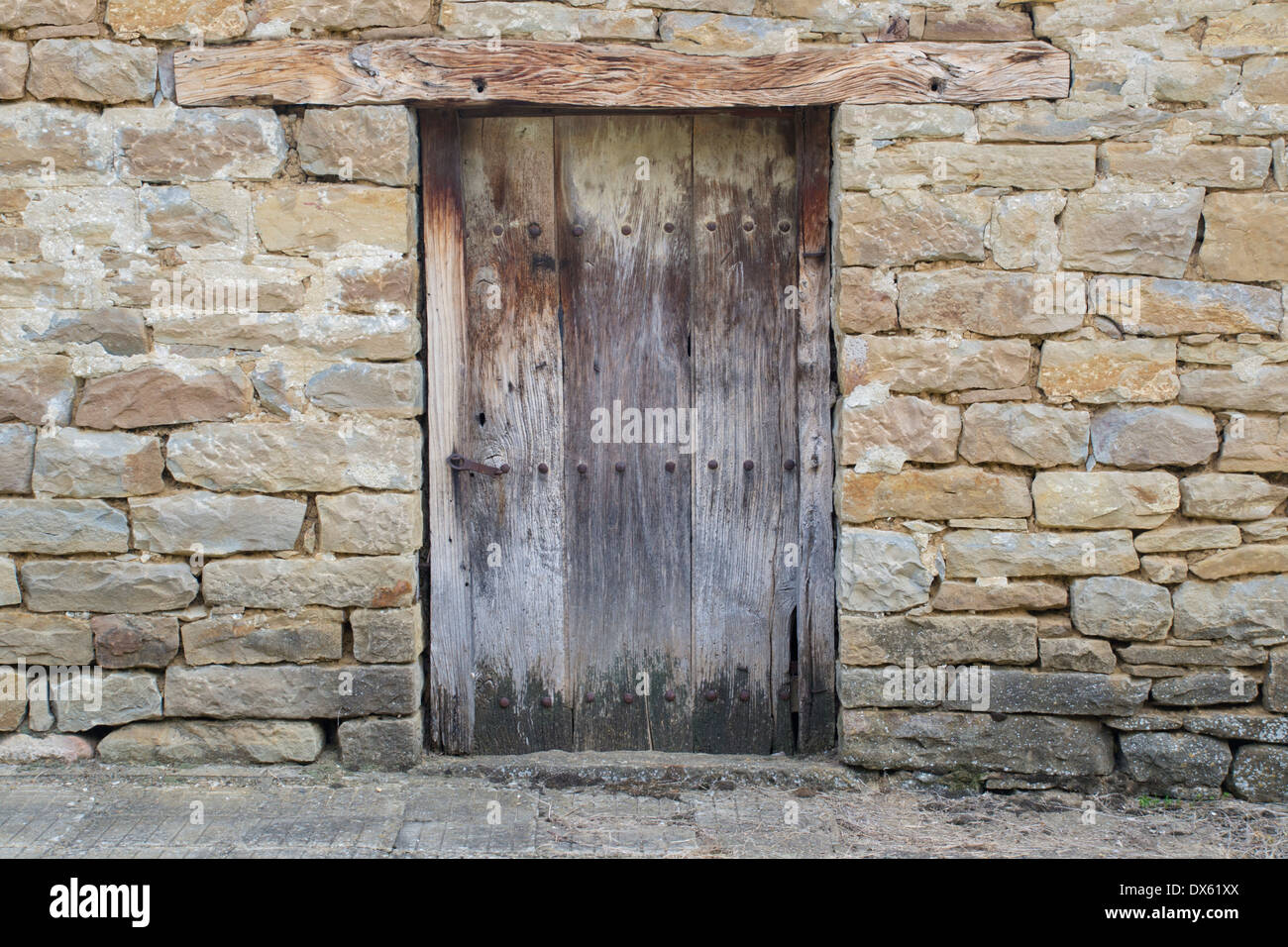 Stone wall with an old rustic massive wooden door Stock Photo 67745410