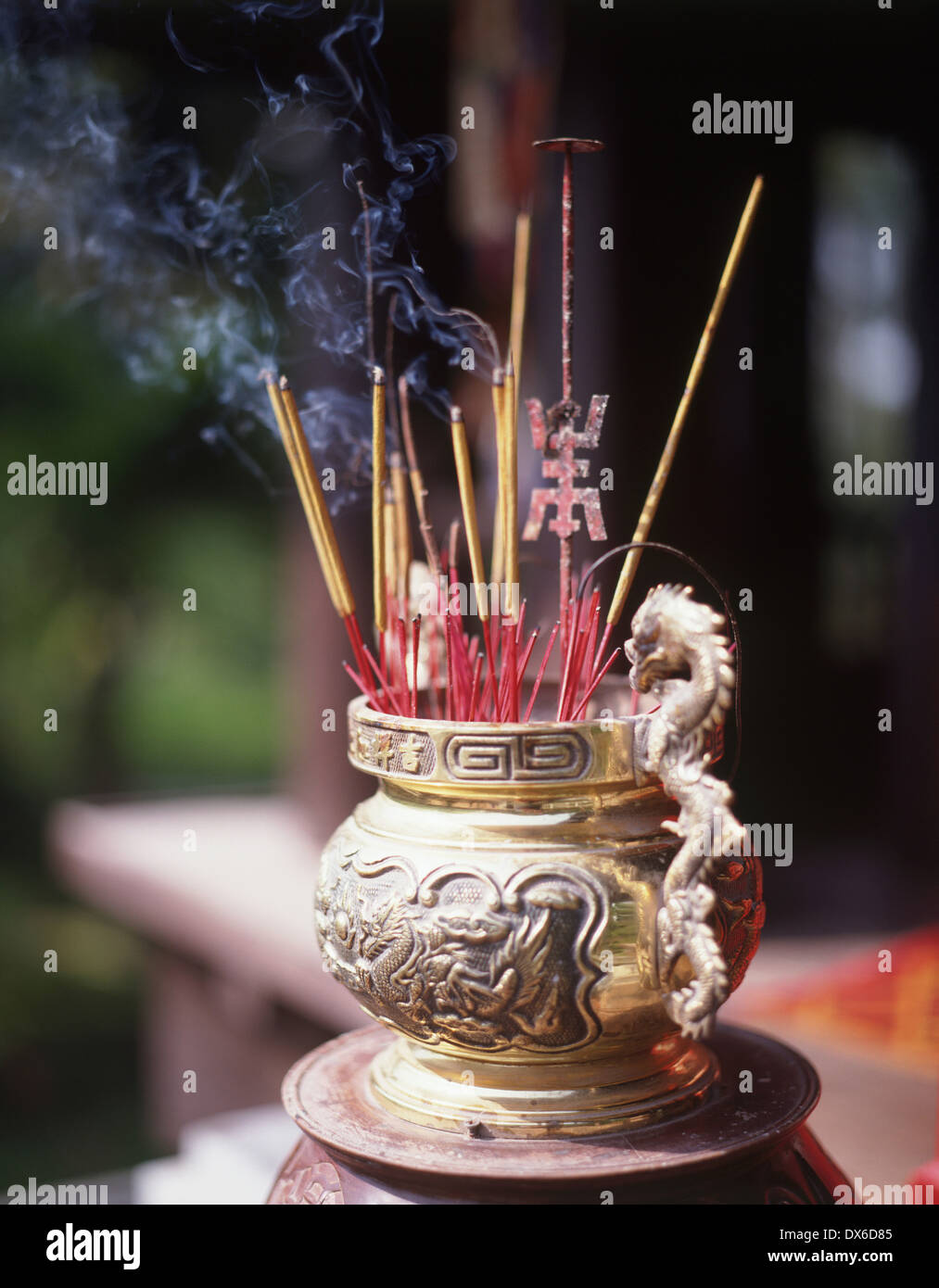 An incense burner, with lit incense sticks wafting prayers upwards. A
