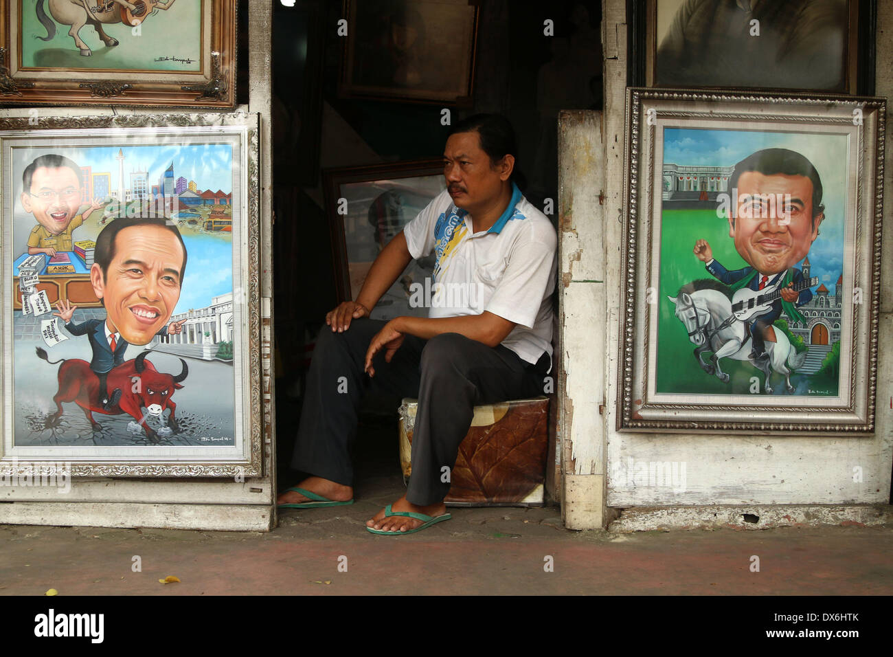 Jakarta, DKI Jakarta, Indonesia. 19th Mar, 2014. An artist painter sits near display of a painting of Jakarta Governor Joko Widodo( Left Below) and A Dangdut Musician, Rhoma Irama (Right Below) at Street Painting Shop Vendor in Jakarta. March 19, 2014 . Joko Widodo who is running for president for the Indonesian Democratic Party of Struggle (PDI-P) and Rhoma Irama a president candidate for the National Awakening Party (PKB). Credit:  Jeff Aries/ZUMAPRESS.com/Alamy Live News Stock Photo