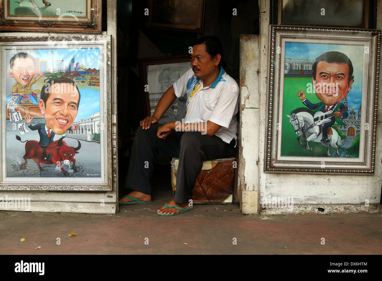 Jakarta, DKI Jakarta, Indonesia. 19th Mar, 2014. An artist painter sits near display of a painting of Jakarta Governor Joko Widodo( Left Below) and A Dangdut Musician, Rhoma Irama (Right Below) at Street Painting Shop Vendor in Jakarta. March 19, 2014 . Joko Widodo who is running for president for the Indonesian Democratic Party of Struggle (PDI-P) and Rhoma Irama a president candidate for the National Awakening Party (PKB). Credit:  Jeff Aries/ZUMAPRESS.com/Alamy Live News Stock Photo