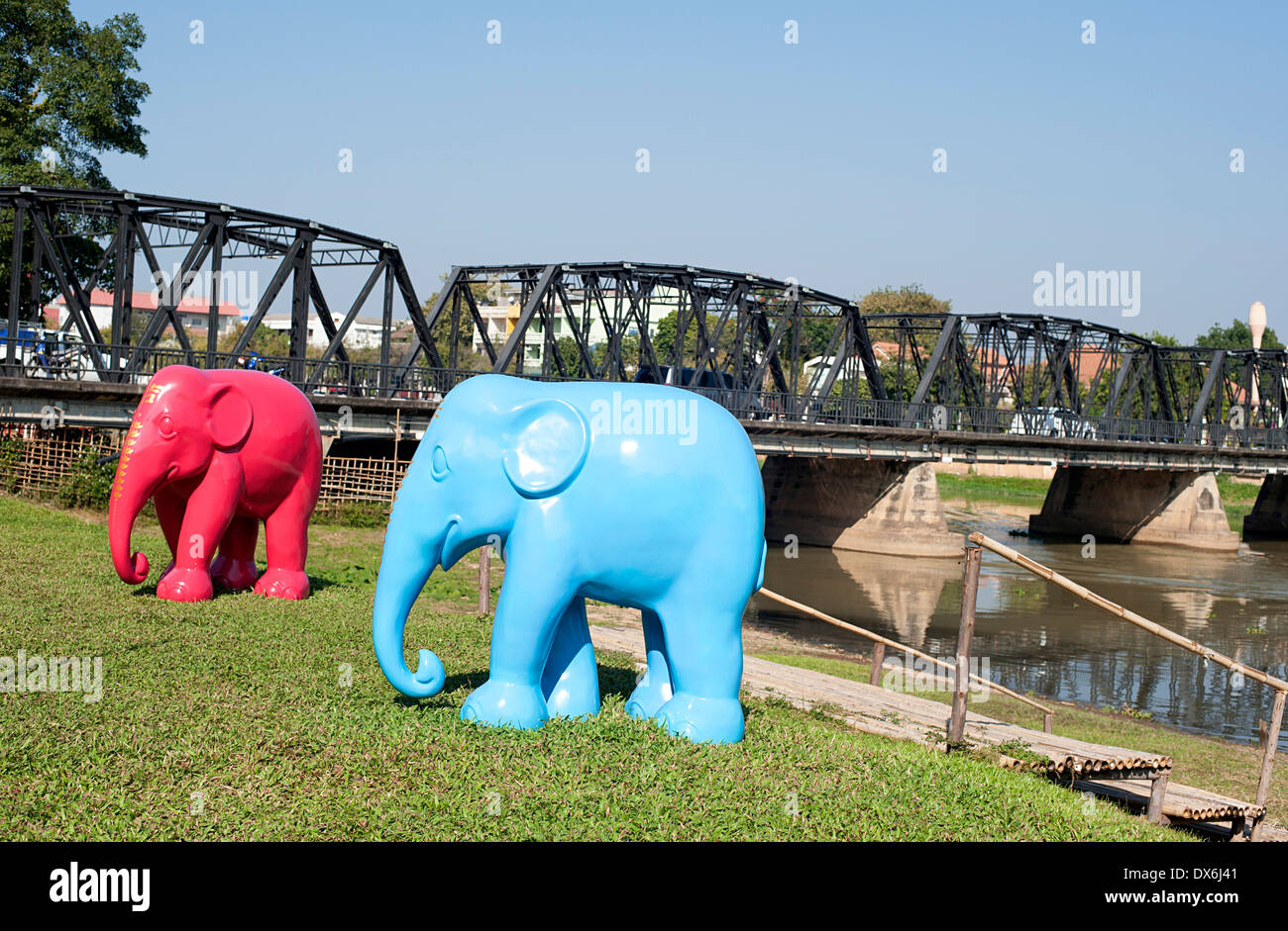 Blue and red elephant statues stand on the lawn of a restaurant in front of the  Ping River in Chiang Mai. Stock Photo