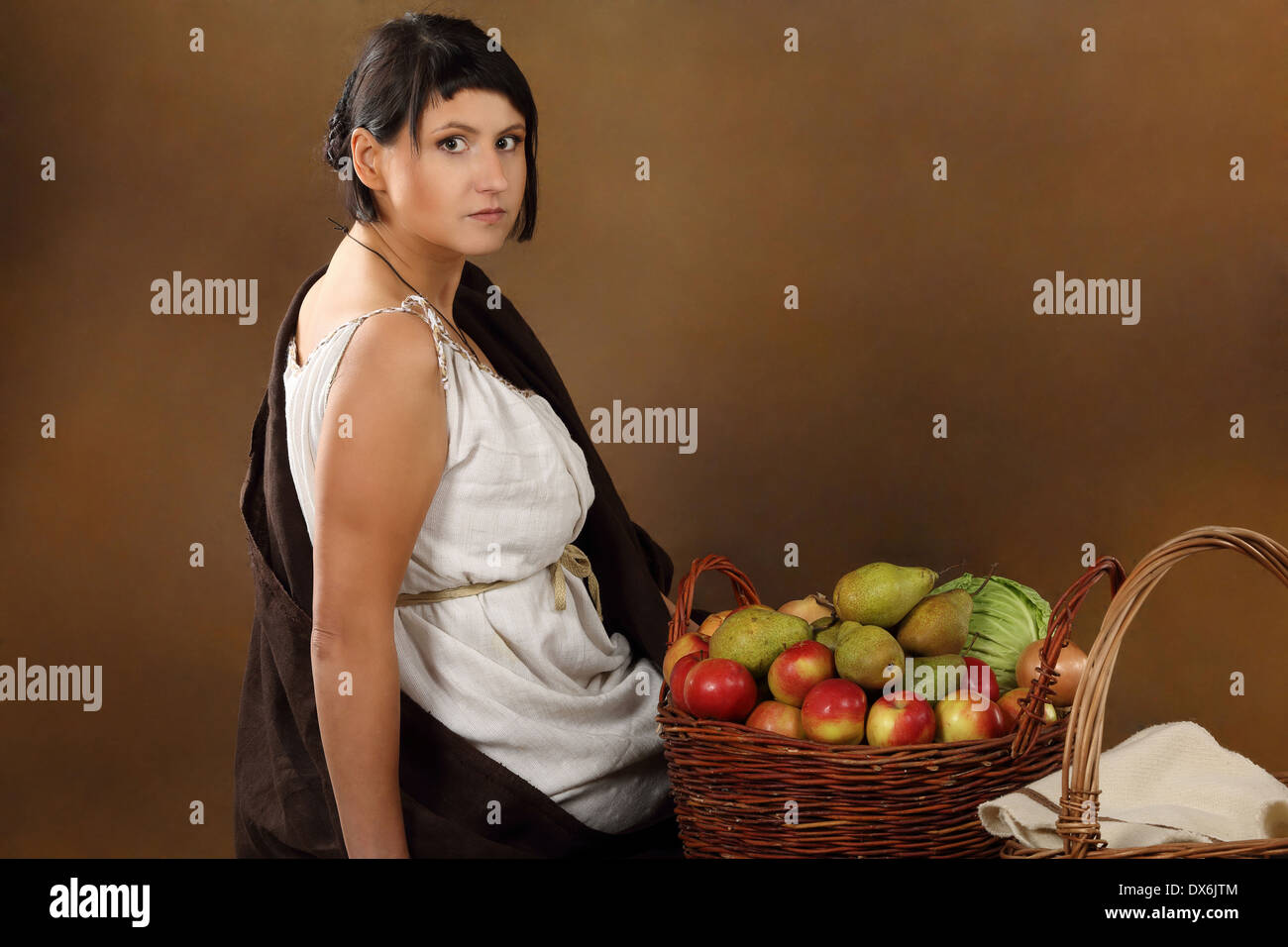 Young Romana with basket full of fruits and vegetables. Concept studio portrait on brown background. Stock Photo
