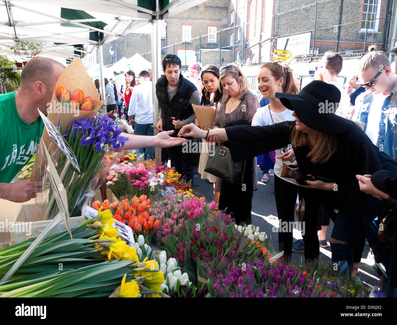 Woman paying with cash buying spring tulips from bulb cut flowers seller trader Columbia Road Flower Market East London E2 England UK   KATHY DEWITT Stock Photo