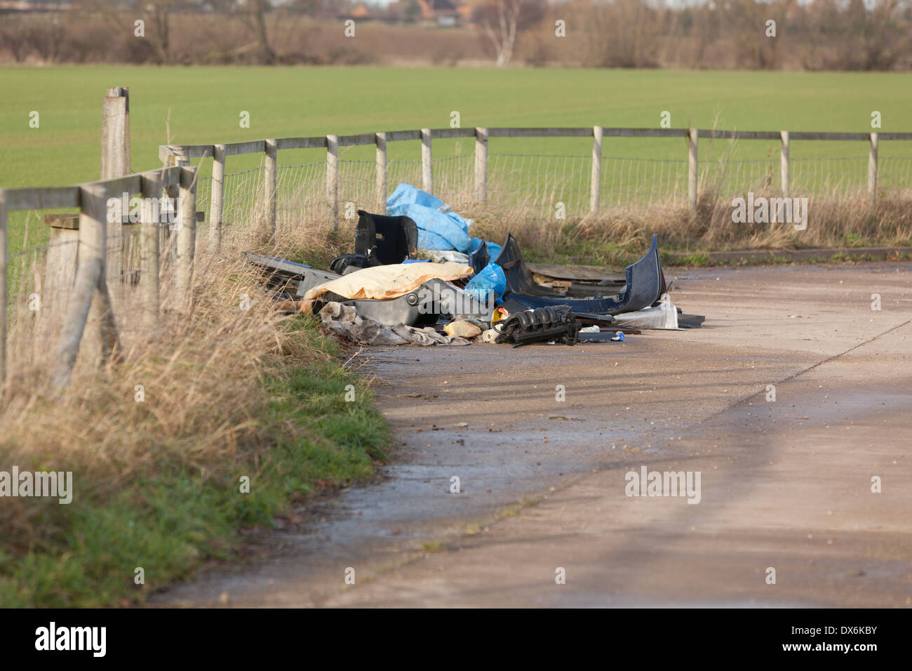 Flytipped car parts and other debris in a layby next to farmland Stock