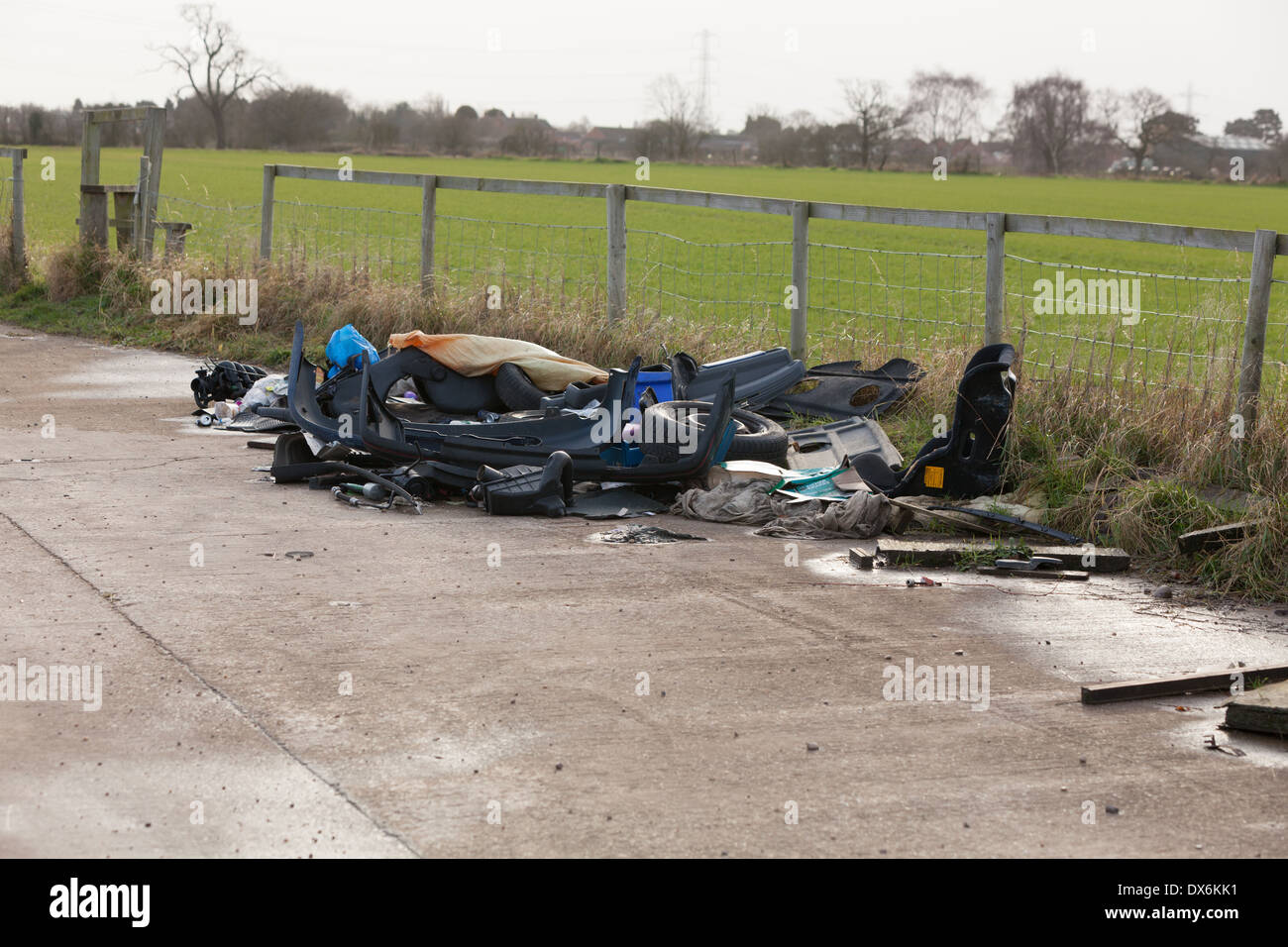 Flytipped car parts and other debris in a layby next to farmland Stock