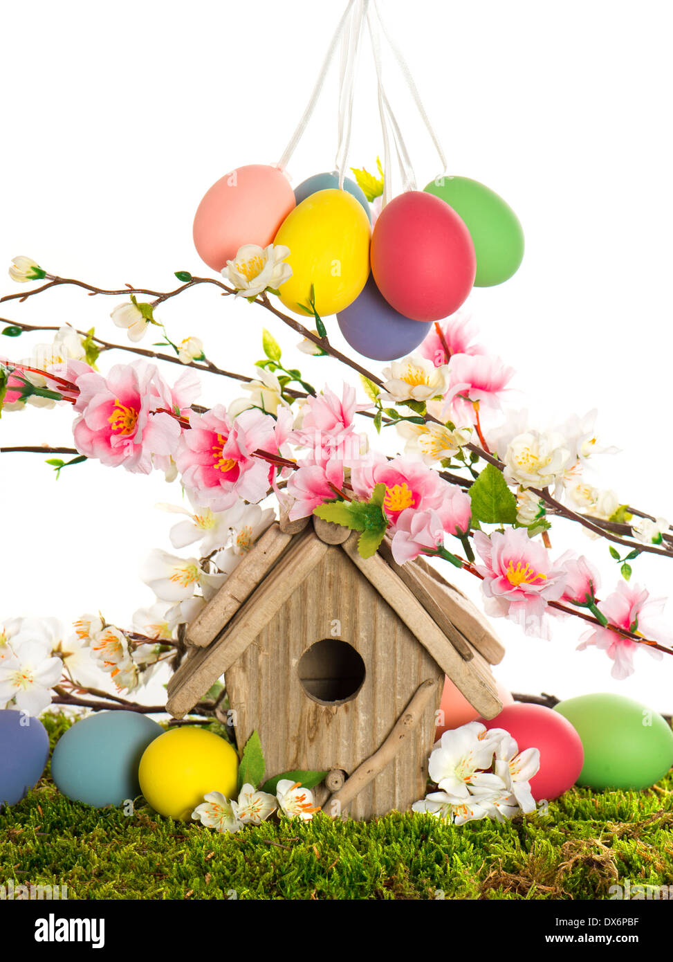 colorful easter decoration with birdhouse and eggs on green grass. spring apple and cherry blossoming Stock Photo