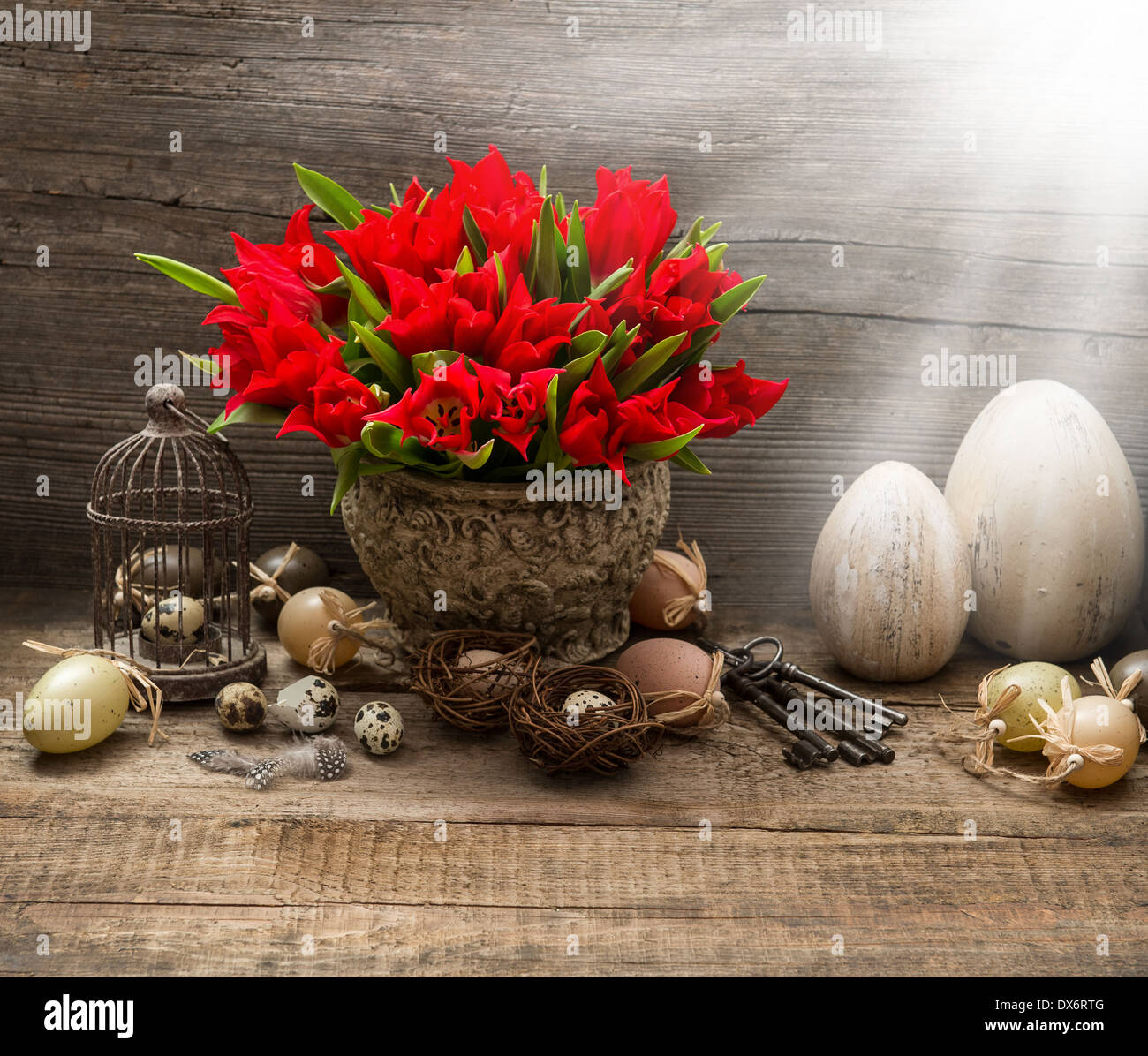 vintage easter composition with eggs and red tulips. nostalgic still life home interior with light beams Stock Photo