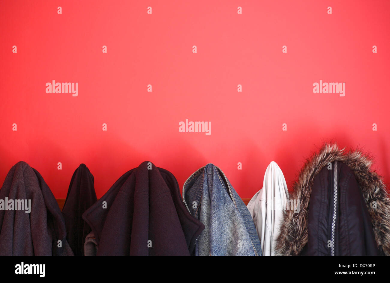 Coats and jackets hanging in a red painted cloakroom Stock Photo Alamy