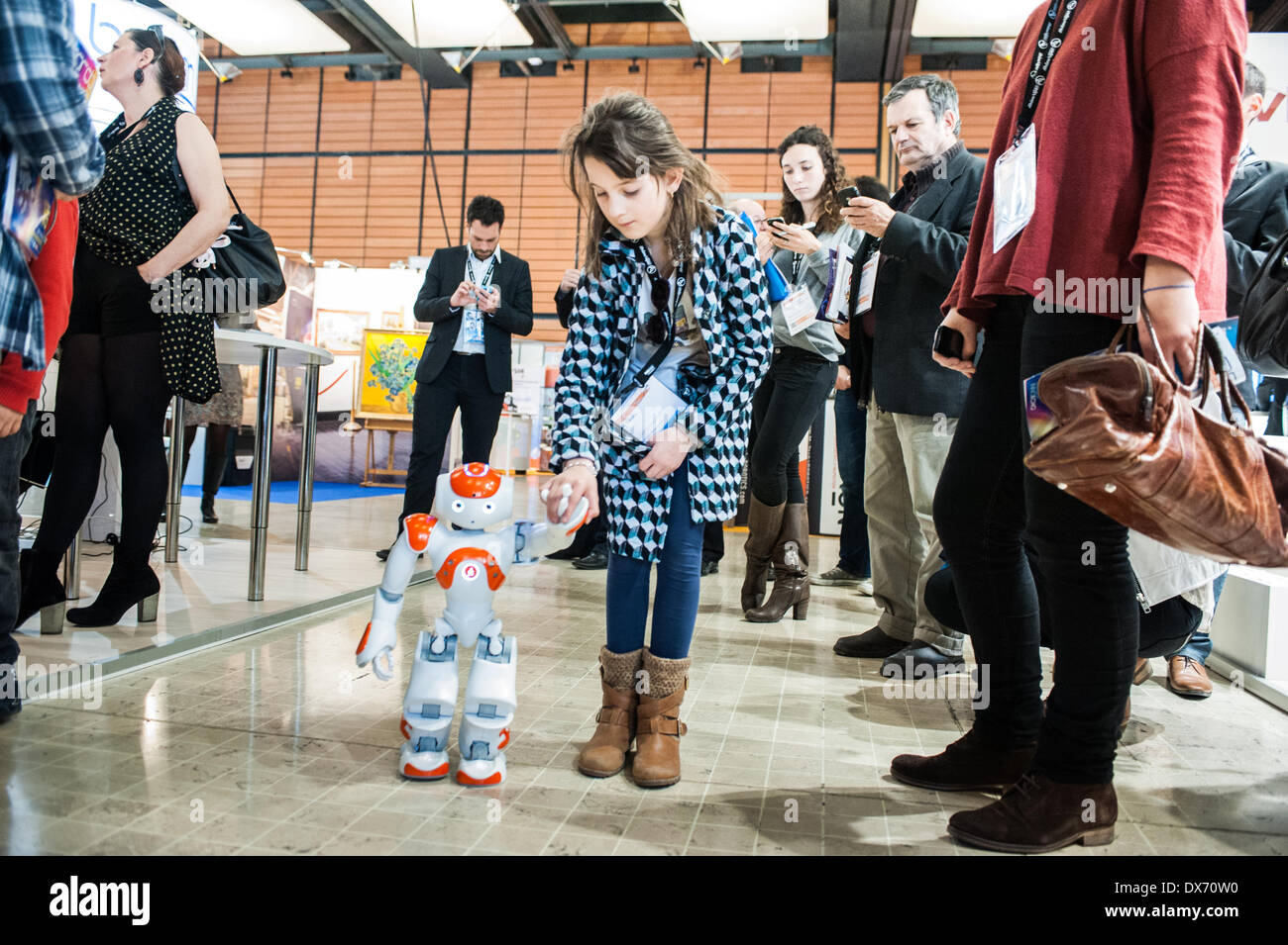 Lyon, France - 19 March 2014: Elora, 8, walks hand by hand with NAO Robot by Aldebaran at Innorobo 2014, the biggest fair in Europe for robotics. Credit:  Piero Cruciatti/Alamy Live News Stock Photo