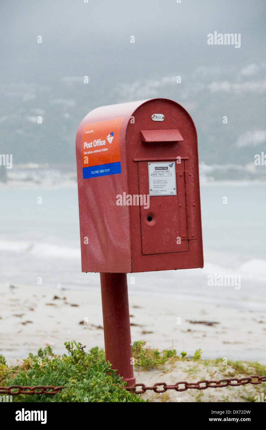 Red metal postbox on a beach Stock Photo