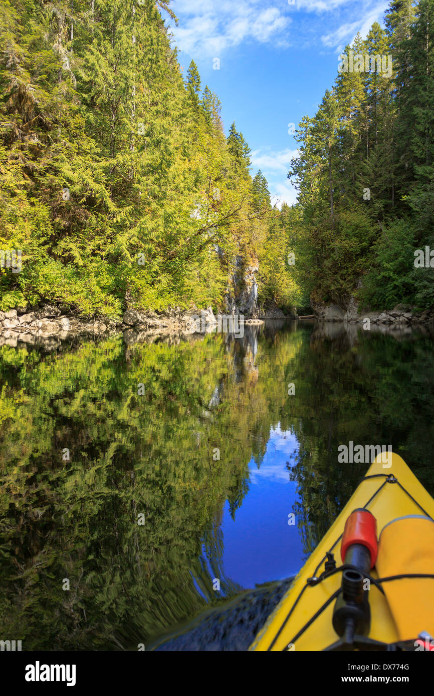 A kayak moves through the calm, reflective waters of the Marble River, BC. Stock Photo