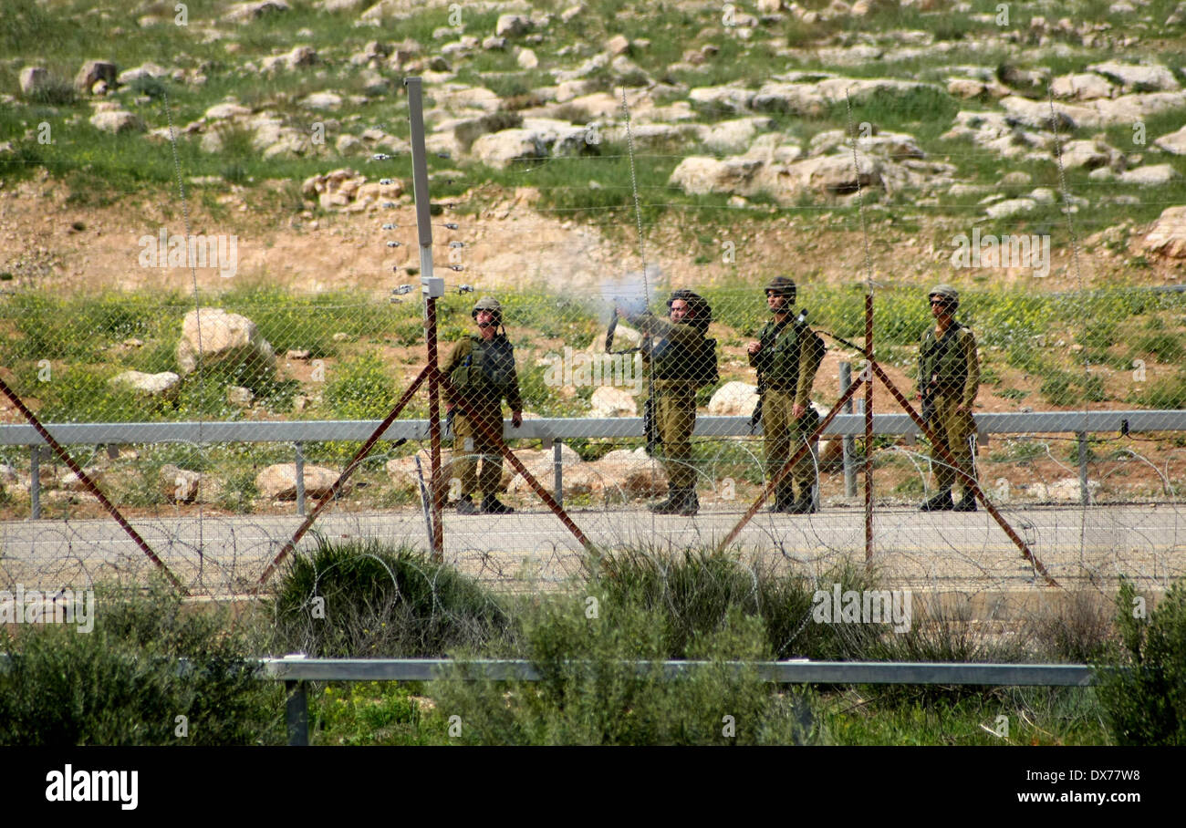 Hebron, West Bank. 19th Mar, 2014. Israeli soldiers shoot at Palestinian protesters during clashes after Palestinian teenager Yussef Shawamreh was killed, near security fence in the West Bank city of Hebron on March 19, 2014. Shawamreh, 16 years old, was shot near the Palestinian village of al-Ramadin, south of Hebron, when he and three of his friends were attempting to cross the separation fence between Israel and the Palestinian territories. Credit:  Mamoun Wazwaz/Xinhua/Alamy Live News Stock Photo