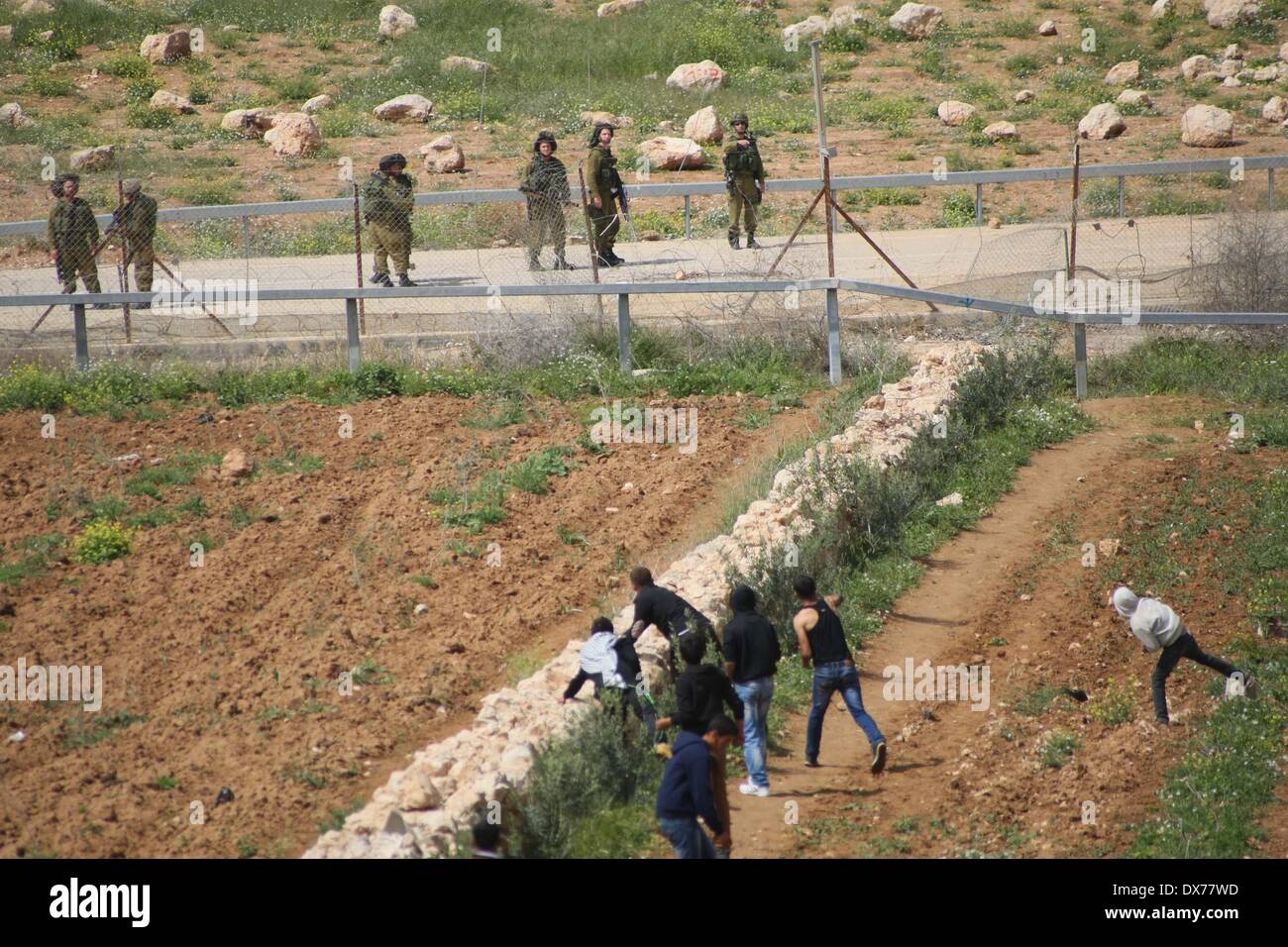 Hebron, West Bank. 19th Mar, 2014. Palestinian protester hurl stones at Israeli soldiers during clashes after Palestinian teenager Yussef Shawamreh was killed, near security fence in the West Bank city of Hebron on March 19, 2014. Shawamreh, 16 years old, was shot near the Palestinian village of al-Ramadin, south of Hebron, when he and three of his friends were attempting to cross the separation fence between Israel and the Palestinian territories. Credit:  Mamoun Wazwaz/Xinhua/Alamy Live News Stock Photo