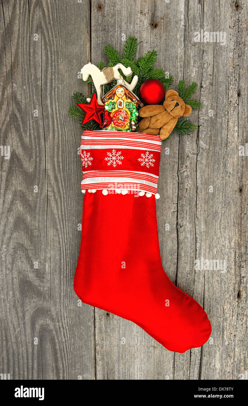 christmas stocking with nostalgic vintage toy decoration and pine branch over wooden background Stock Photo
