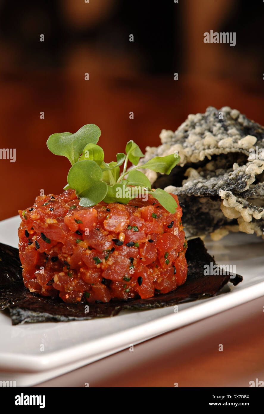 Raw ahi tuna tartare appetizer atop a sheet of nori and garnished with