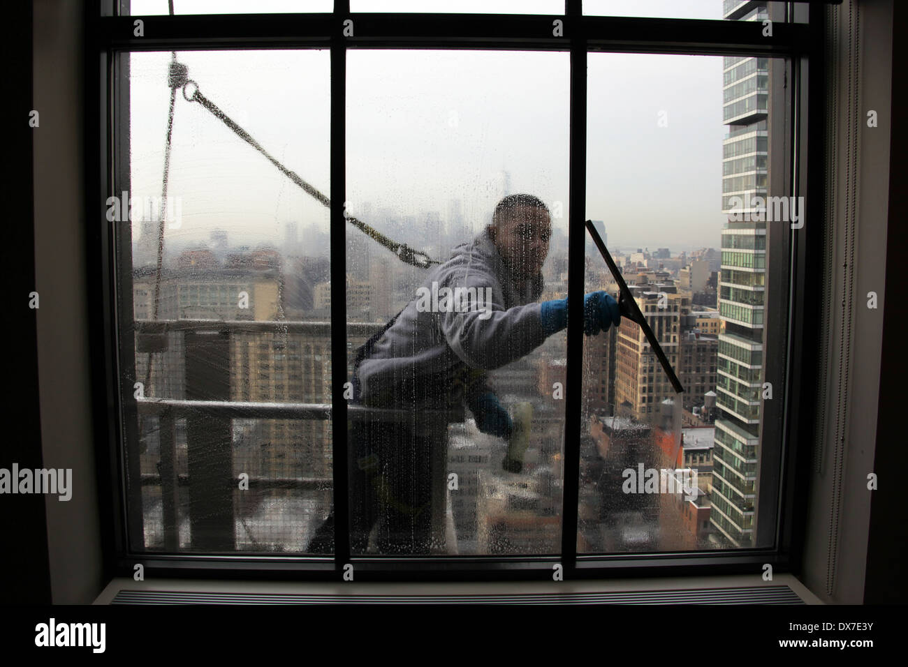 Inside view of a window washer standing on scaffolding and secured by harness while cleaning a New York City skyscraper windows Stock Photo