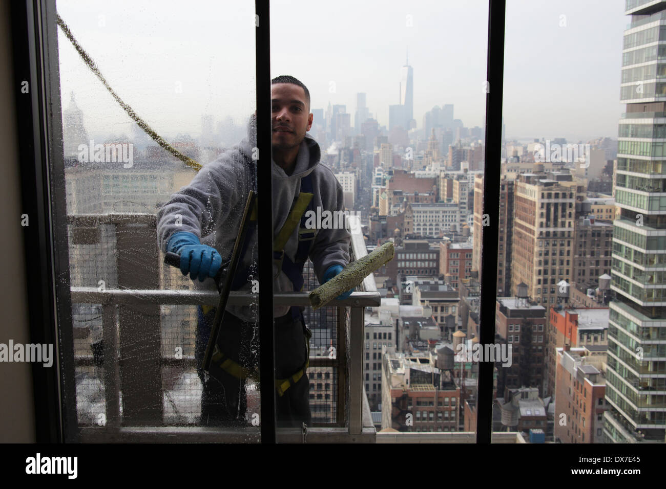 Inside view of a window washer standing on scaffolding and secured by harness while cleaning a New York City skyscraper windows Stock Photo