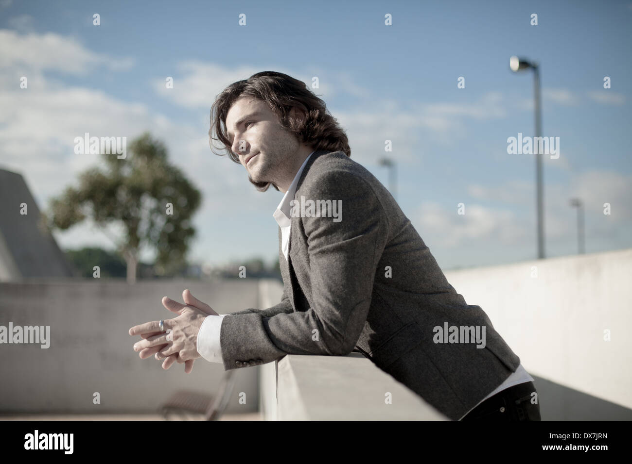 A young male model leaning against a wall with a blue sky behind him Stock Photo