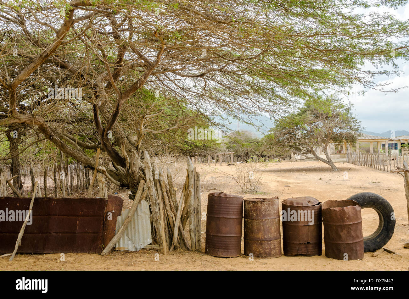 Rusted barrels making a fence in a rural village in La Guajira, Colombia Stock Photo