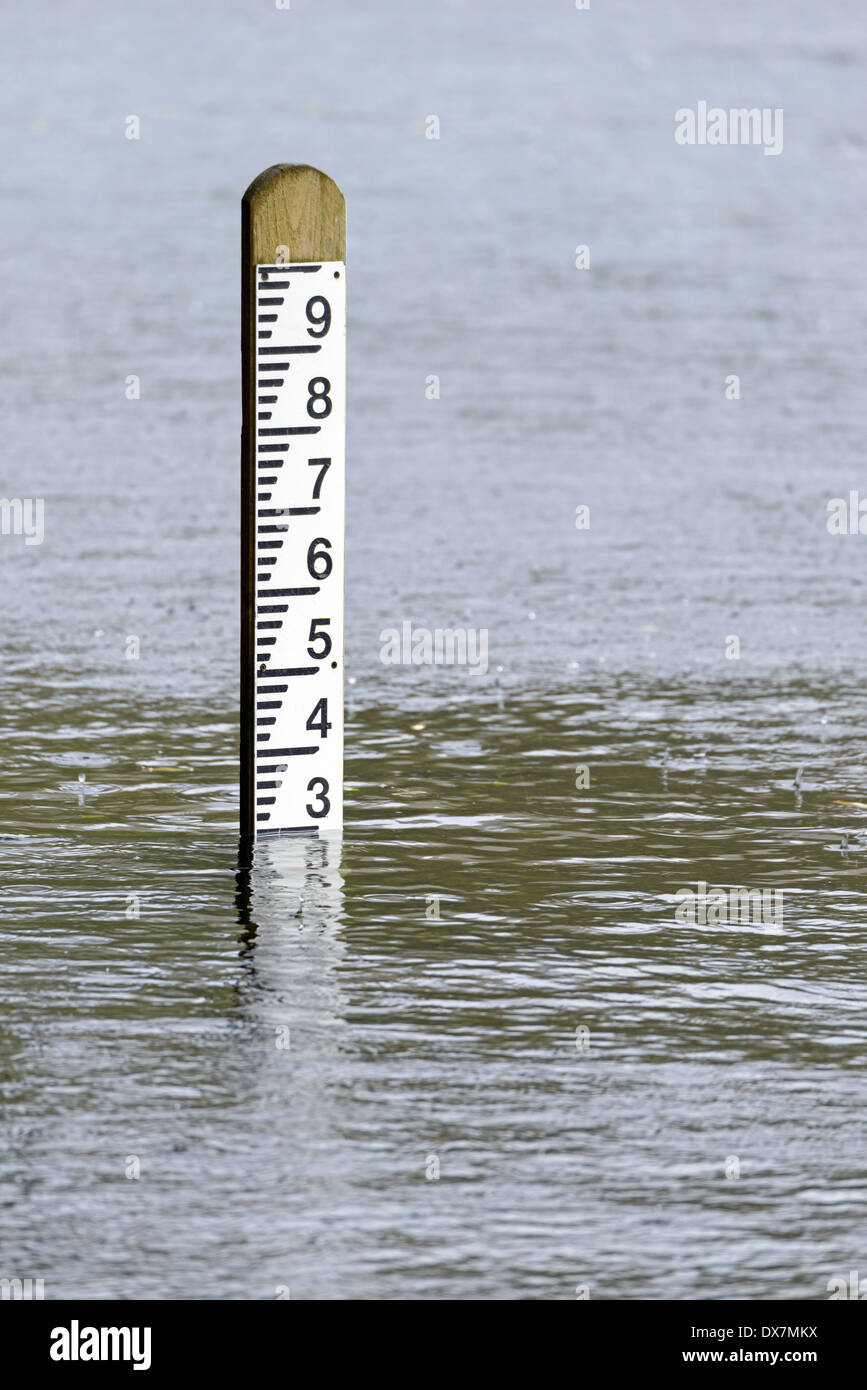 Flood level depth marker post with rain falling into the surrounding water Stock Photo