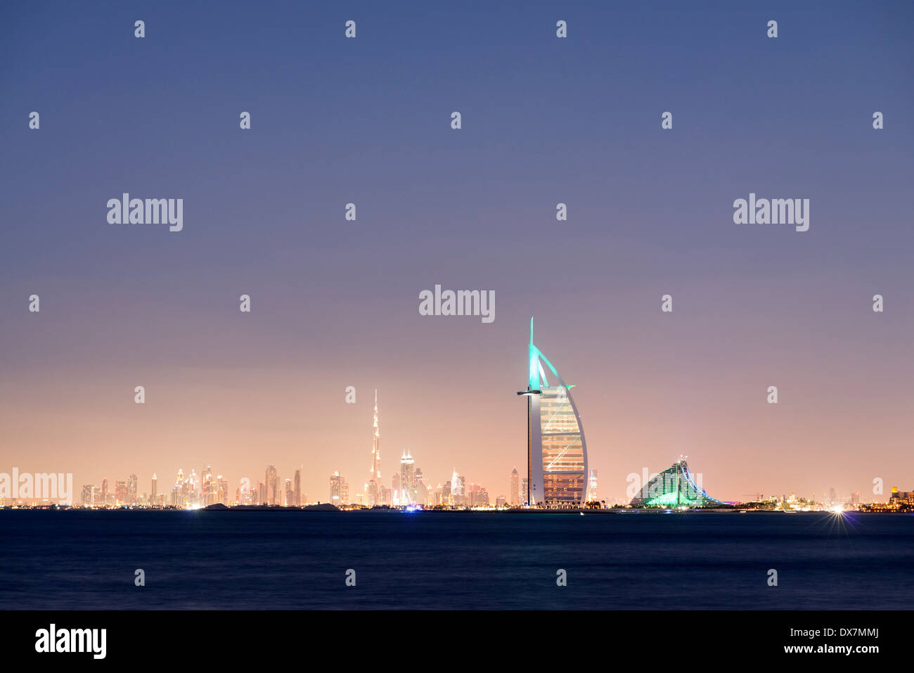 Night skyline across sea to luxury Burj al Arab hotel and city of Dubai with Burj Khalifa tower in distance United Arab Emirates Stock Photo