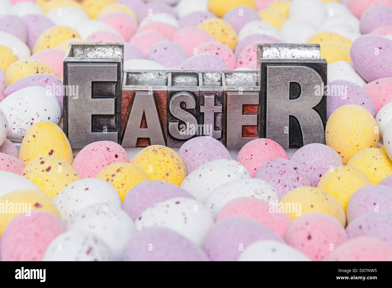 The word Easter in old metal letterpress surrounded by candy covered mini chocolate eggs. Stock Photo