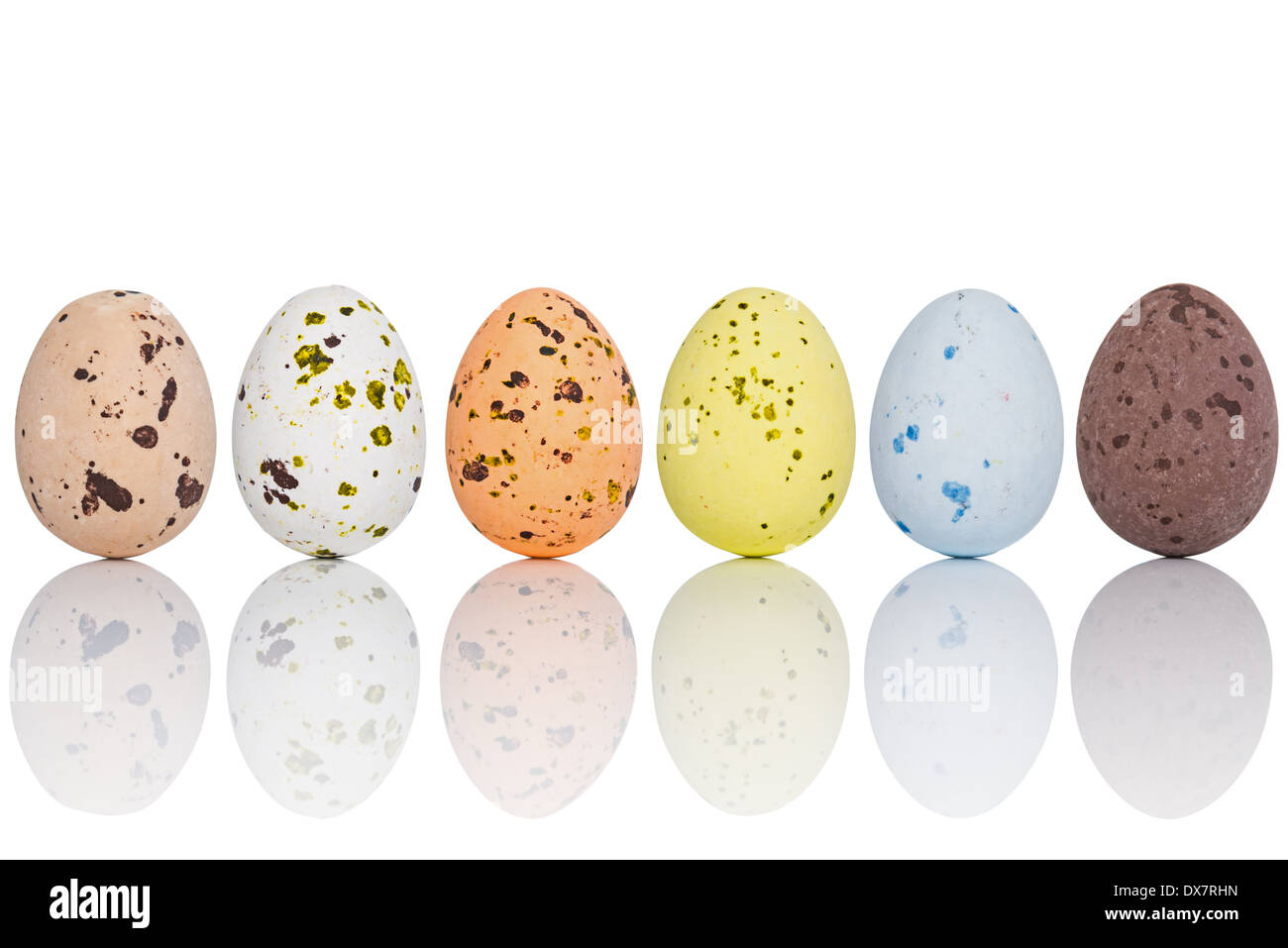 Six candy coated chocolate Easter eggs in a line, isolated on white