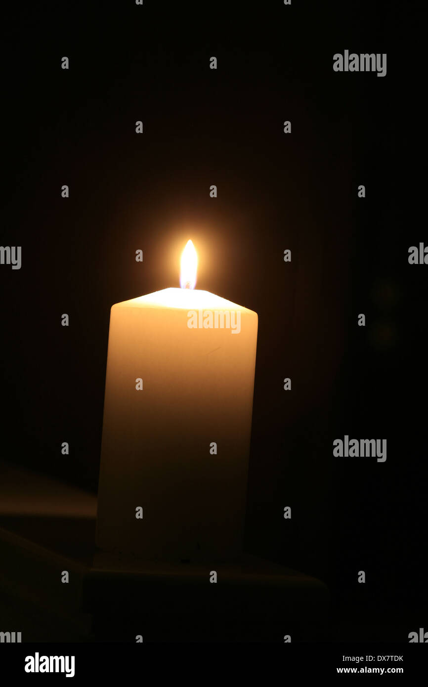 a white burning candle with black background Stock Photo - Alamy