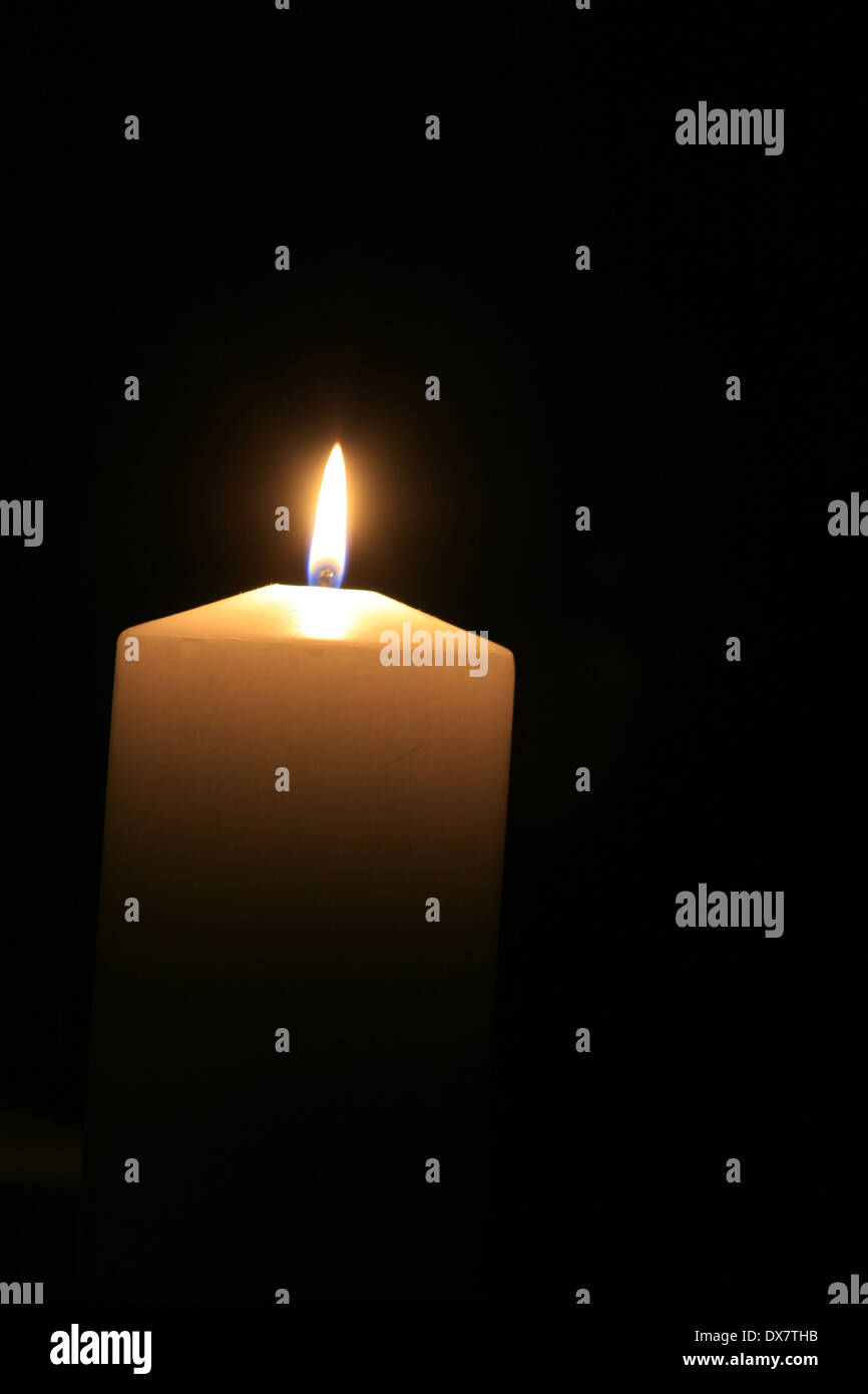 a white burning candle with black background Stock Photo - Alamy