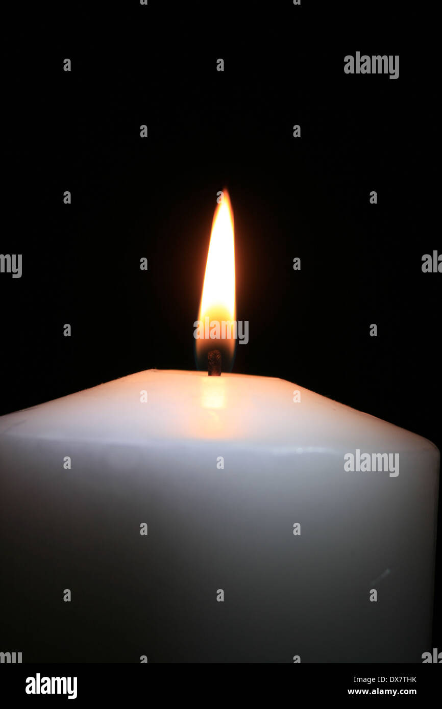 a white burning candle with black background Stock Photo - Alamy