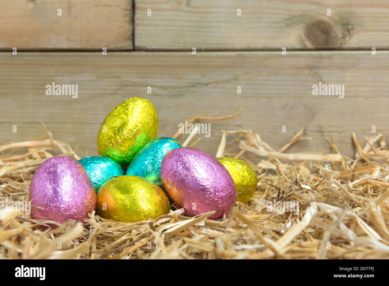 Foil covered chocolate Easter eggs in a straw nest in a barn Stock