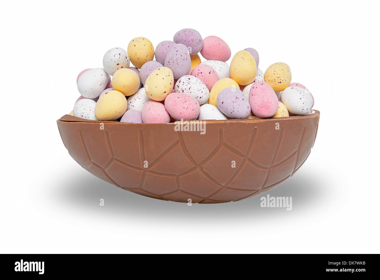 Half a chocolate Easter egg full of mini candy coated eggs, isolated on a white background. Stock Photo