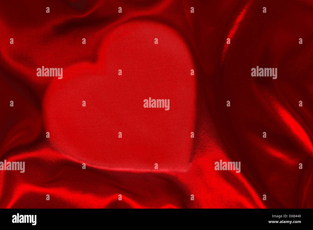 A red silk sheet with heart shape underneath Stock Photo