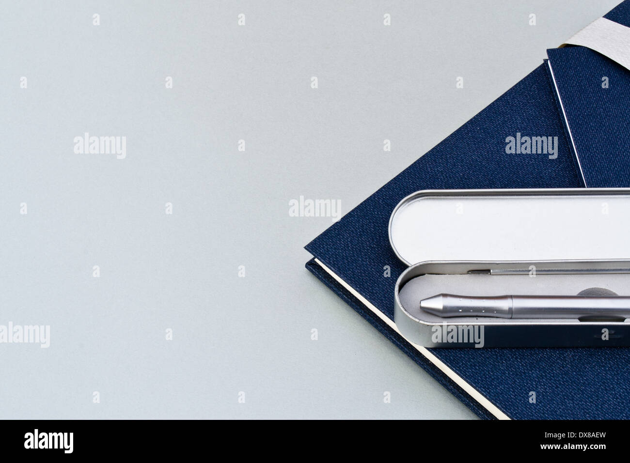 Diary and pen used in an office or business environment. The diary or book is blue and the silver pen is in it's silver case. Stock Photo