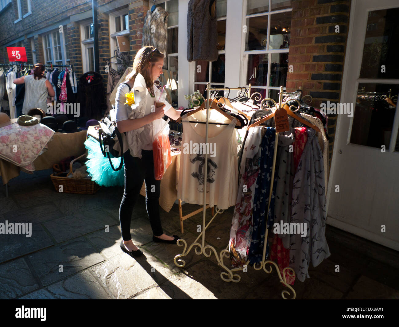 A young woman browsing in a second hand clothing shop at Columbia Road Flower Market London E2 UK KATHY DEWITT Stock Photo