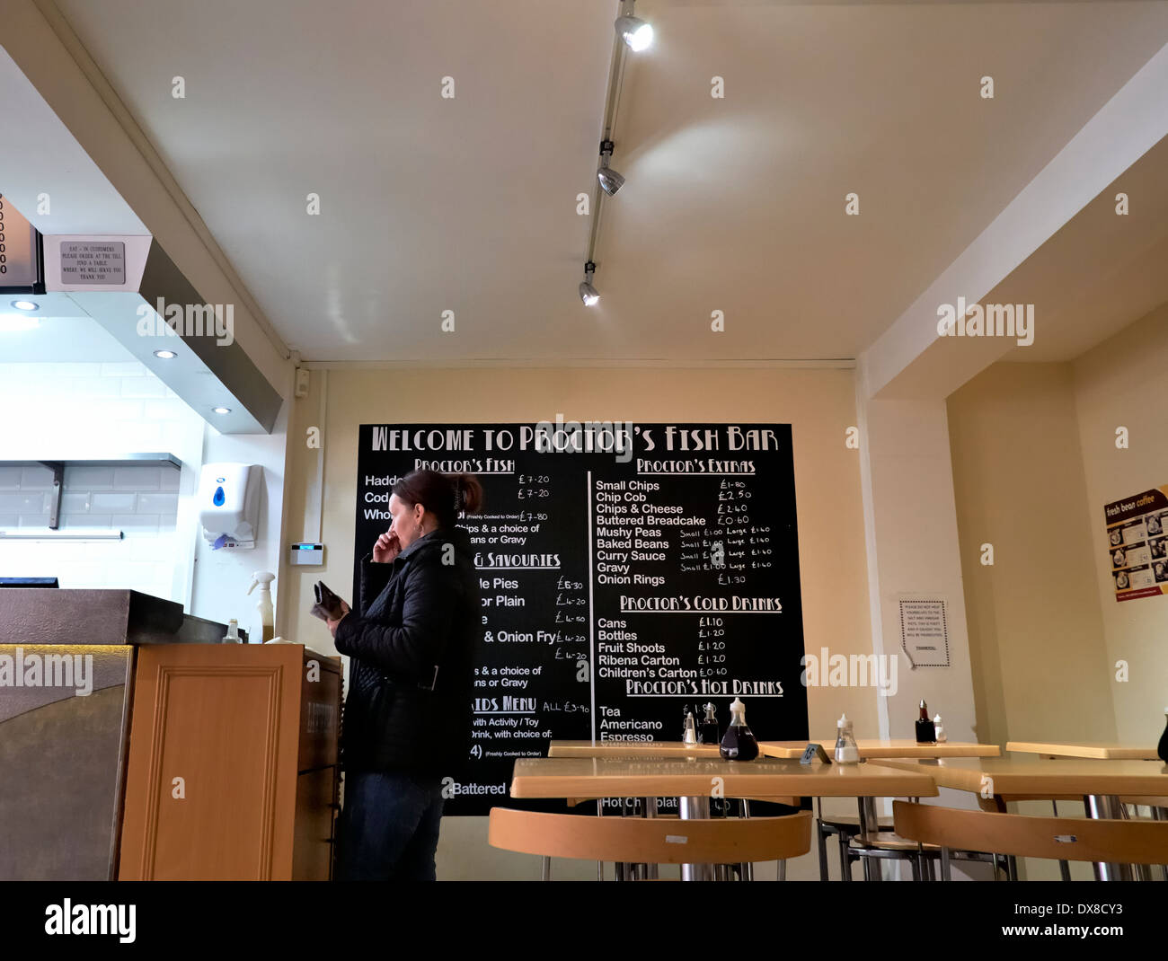 Female waiting to be served in a traditional fish and chip shop Proctors Bakwell Derbyshire England uk Stock Photo