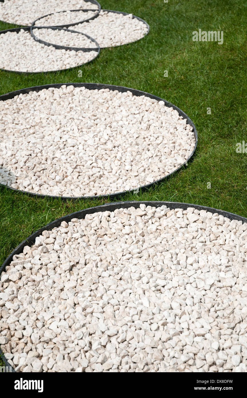Large circles of pale coloured gravel set on a lawn of green grass