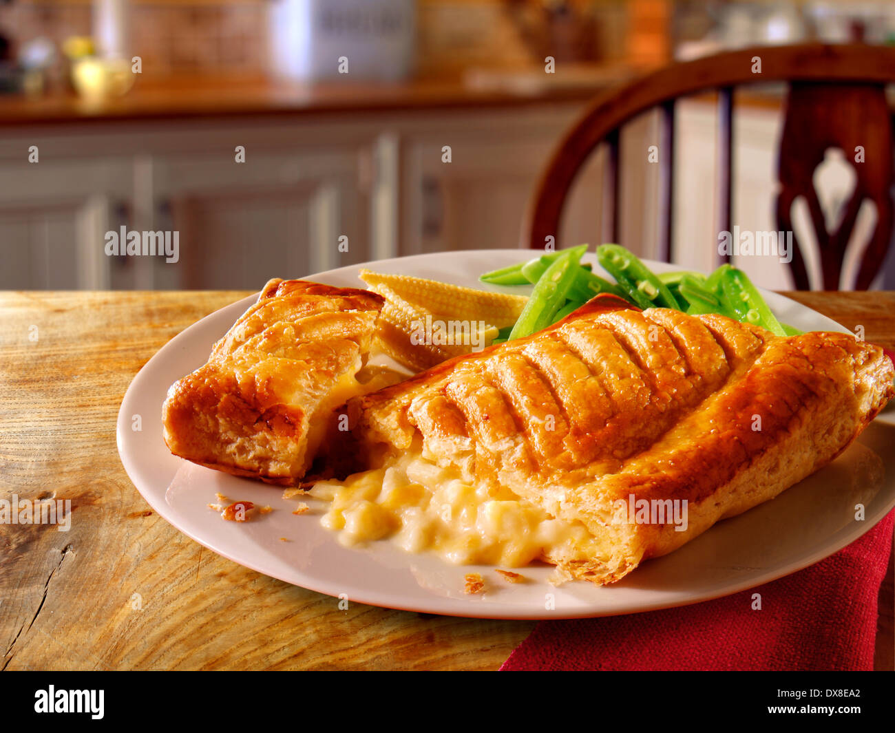 Traditional cheese lattice pasty slice meal served with green beans on a plate in a rustic homely kitchen setting Stock Photo