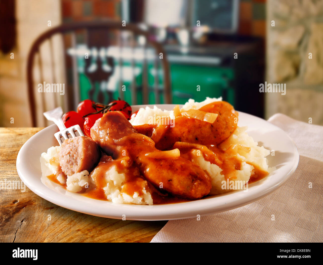 Traditional cooked Sausage and mash served on a white plate in a table setting ready to eat Stock Photo