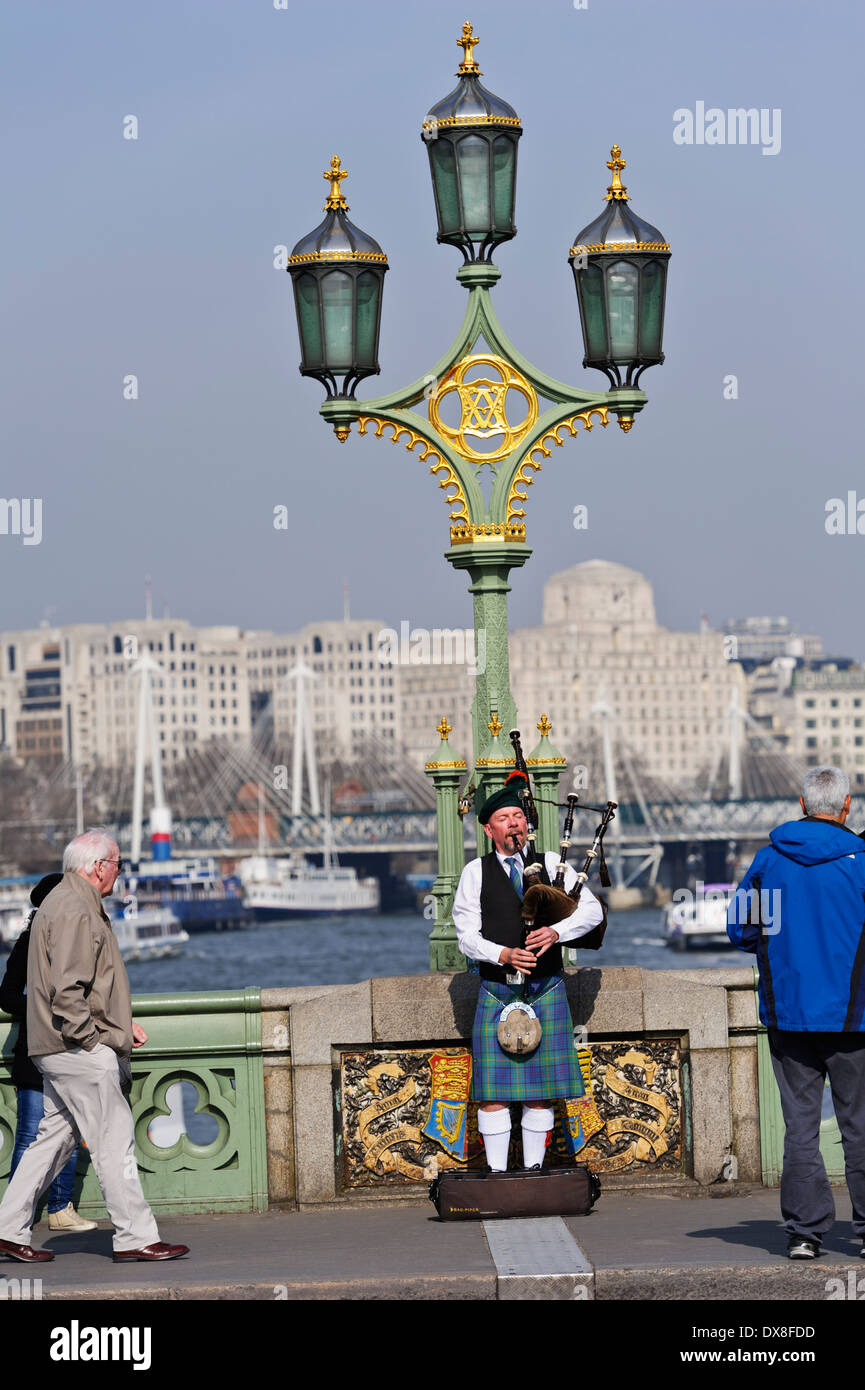 Scottish bagpiper playing music with bagpipe on Westminster bridge