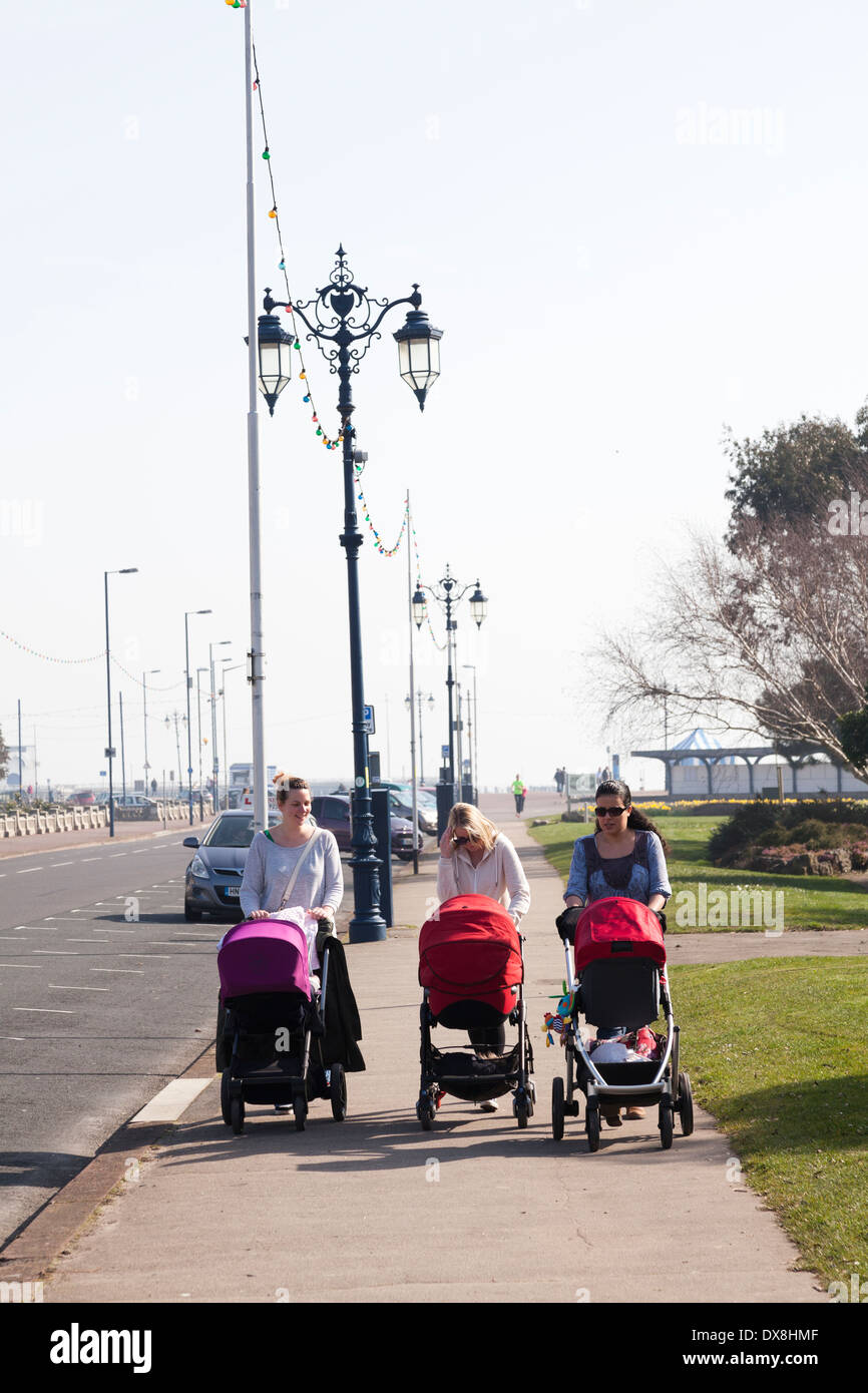Three women pushing baby buggies using width of pavement. Stock Photo