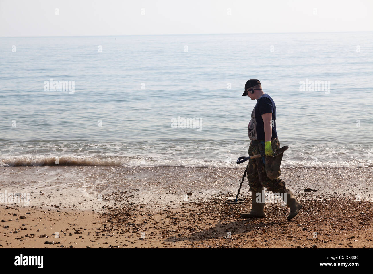 One man using metal detector at waters edge of seaside beach. Stock Photo