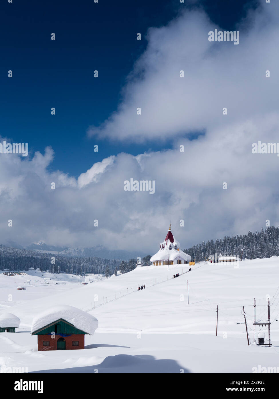 India, Kashmir, Gulmarg, Himalayan Ski Resort, man walking to snow laden Maharani Shiv Ji Temple Stock Photo