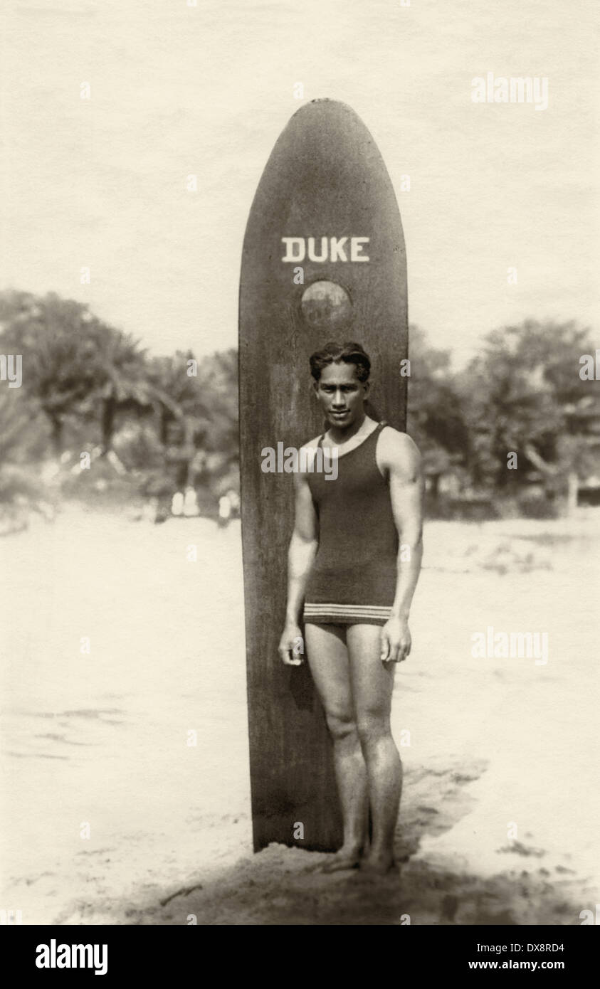 Duke Kahanamoku, the father of modern surfing, standing on a beach in Hawaii with his wooden surfboard, c1912. Stock Photo