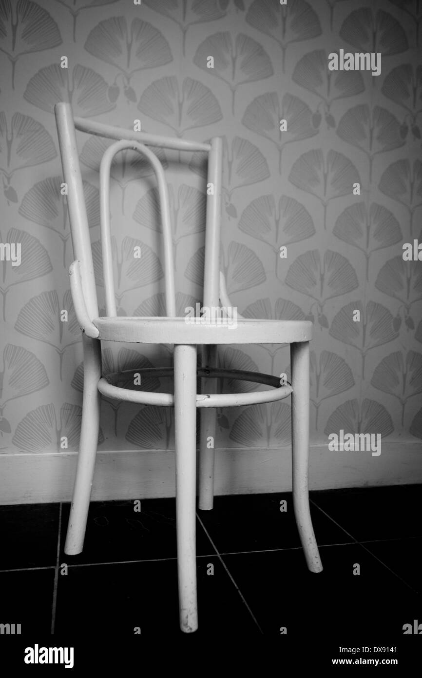 White wooden chair in a wallpapered empty room Stock Photo