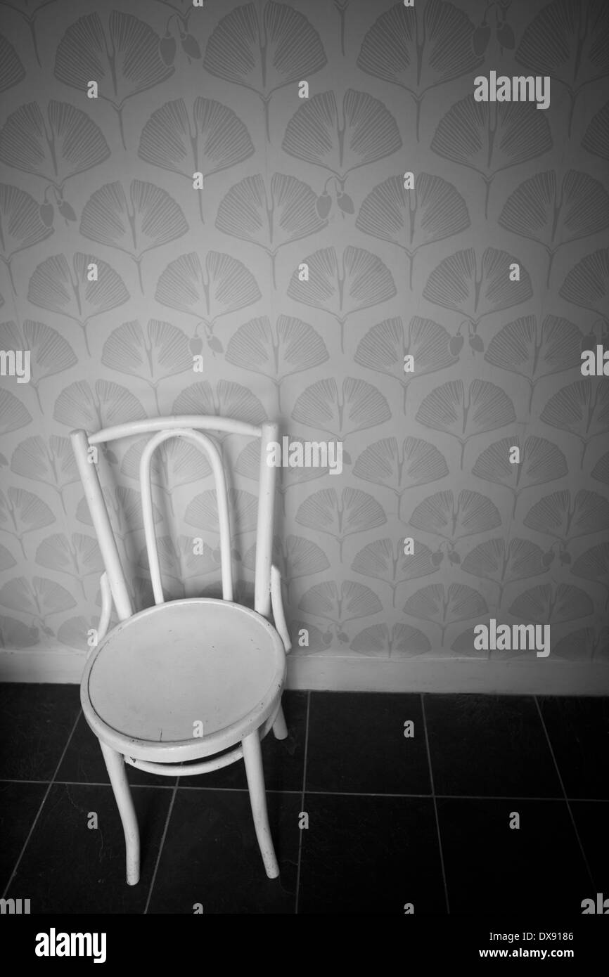White wooden chair in a wallpapered empty room Stock Photo