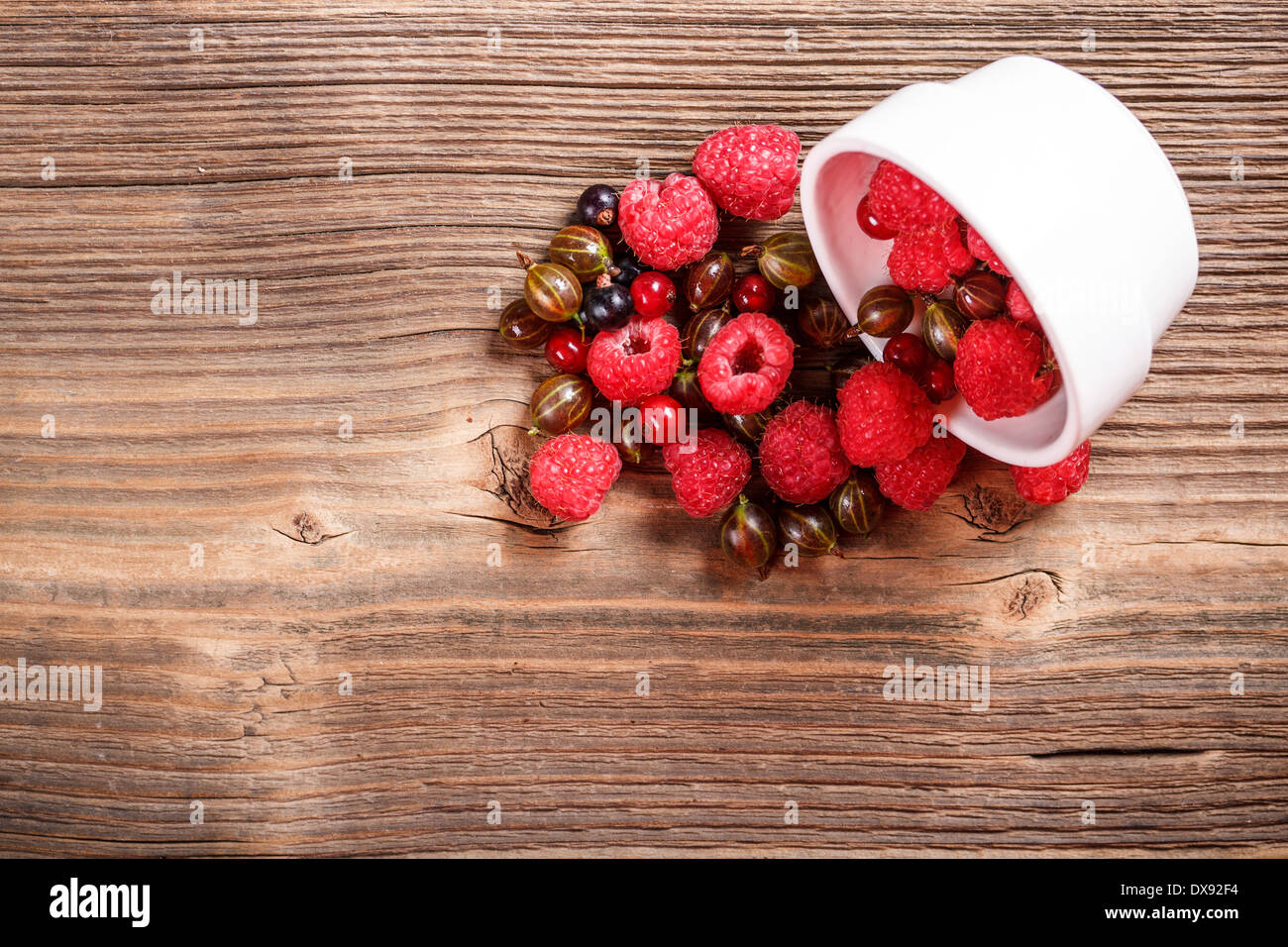 Mixed berries scattered on old wooden board Stock Photo