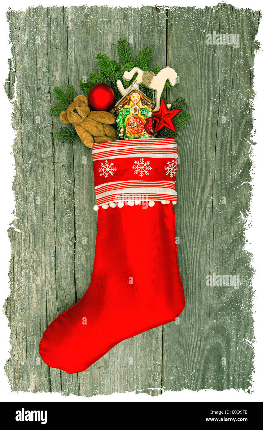 christmas stocking with nostalgic antique toy decoration and pine branch over wooden background. Stock Photo